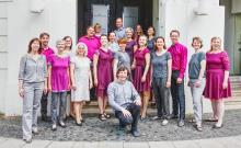 Fotos des Chores in grau und beerenfarbener Kleidung vor dem Weltspiegel-Kino