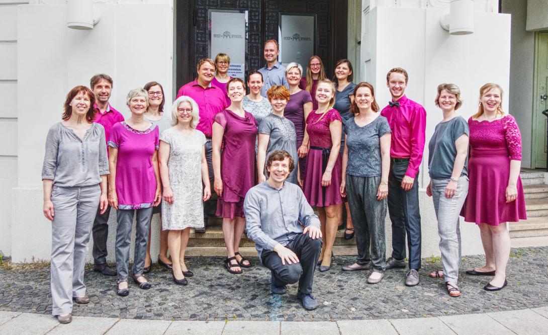Fotos des Chores in grau und beerenfarbener Kleidung vor dem Weltspiegel-Kino