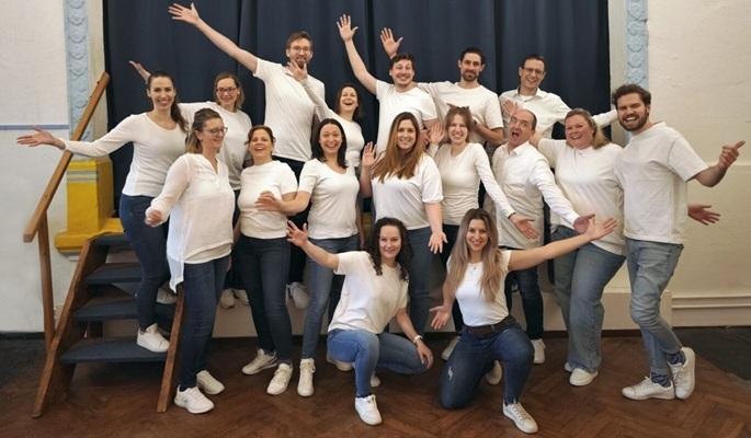 Der Pop-Chor elbtonics fröhlich jubelnd vor einer kleinen Bühne.